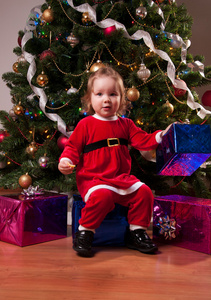 可爱的宝贝女孩在附近圣诞树圣诞老人服装