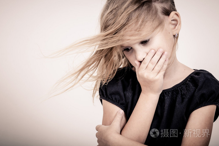 悲伤的金发小女孩站在墙附近的肖像