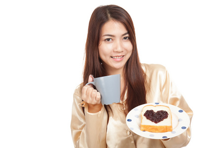 亚洲女人穿着睡衣，咖啡和心形状果酱面包