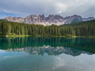 Latemar 山脉和树林，反映在湖 Karersee 在日落时在多云的天气，白云岩 意大利