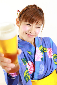 年轻女人穿着日本和服与一杯啤酒