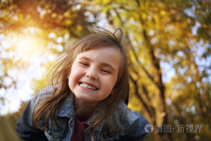 在阳光明媚的公园欢乐的年轻女孩微笑