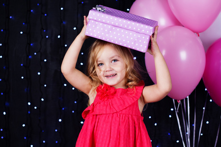 小女孩用粉红的气球和礼品盒