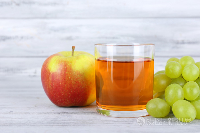 杯新鲜葡萄与灰色的木桌上苹果汁