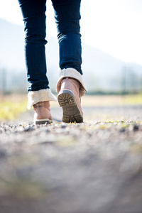 女人穿着牛仔裤和靴子农村小径上行走