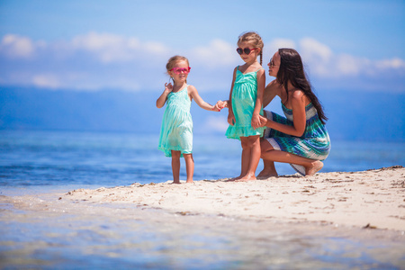 可爱的小女孩和年轻母亲，在热带的白色沙滩，在荒岛上