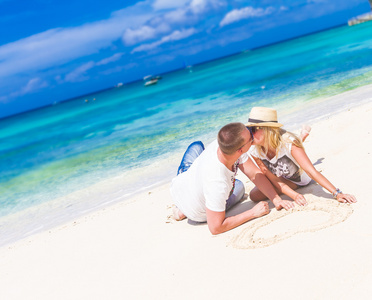 年轻爱夫妇放松砂热带海滩上蓝蓝的天空