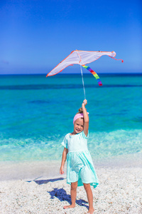 玩在热带海滩上放风筝的小快乐的女孩