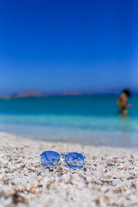 热带海滩上多彩蓝色太阳镜的特写