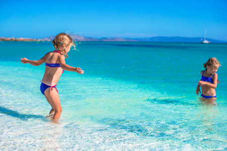 可爱的小女孩在热带海滩有浅层水中的乐趣
