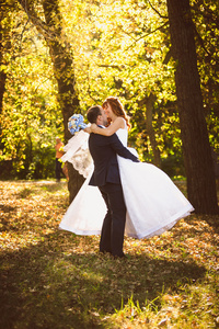 在西装拥抱和纺纱在秋天公园新娘新郎
