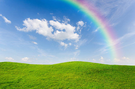绿草与蓝色的天空和作为背景的彩虹