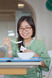 亚洲女孩病人在医院的床上享受餐