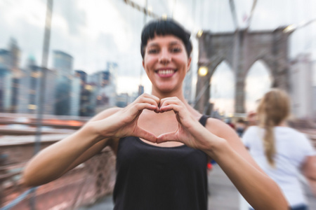 年轻女人用心塑造在布鲁克林大桥上的手