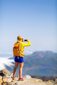 女人的徒步旅行者在山拍照