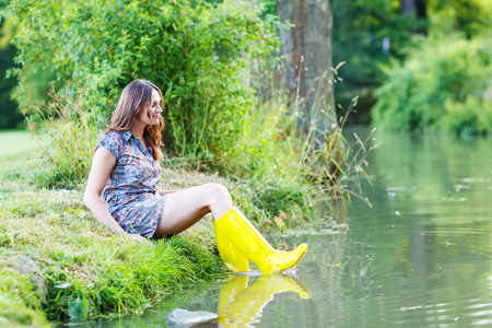 年轻漂亮的女人,坐在黄雨橡皮艇由 r照片