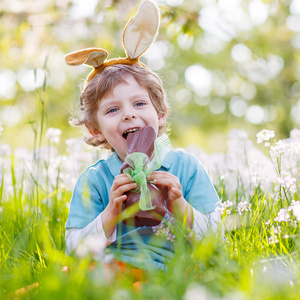 小孩头戴复活节兔子耳朵和吃巧克力