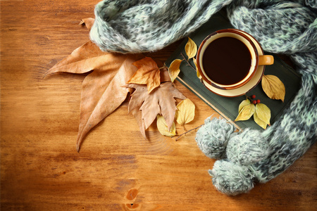 顶视图的杯黑咖啡与秋天的落叶 暖和的围巾和木制背景上的老书。filreted 图像