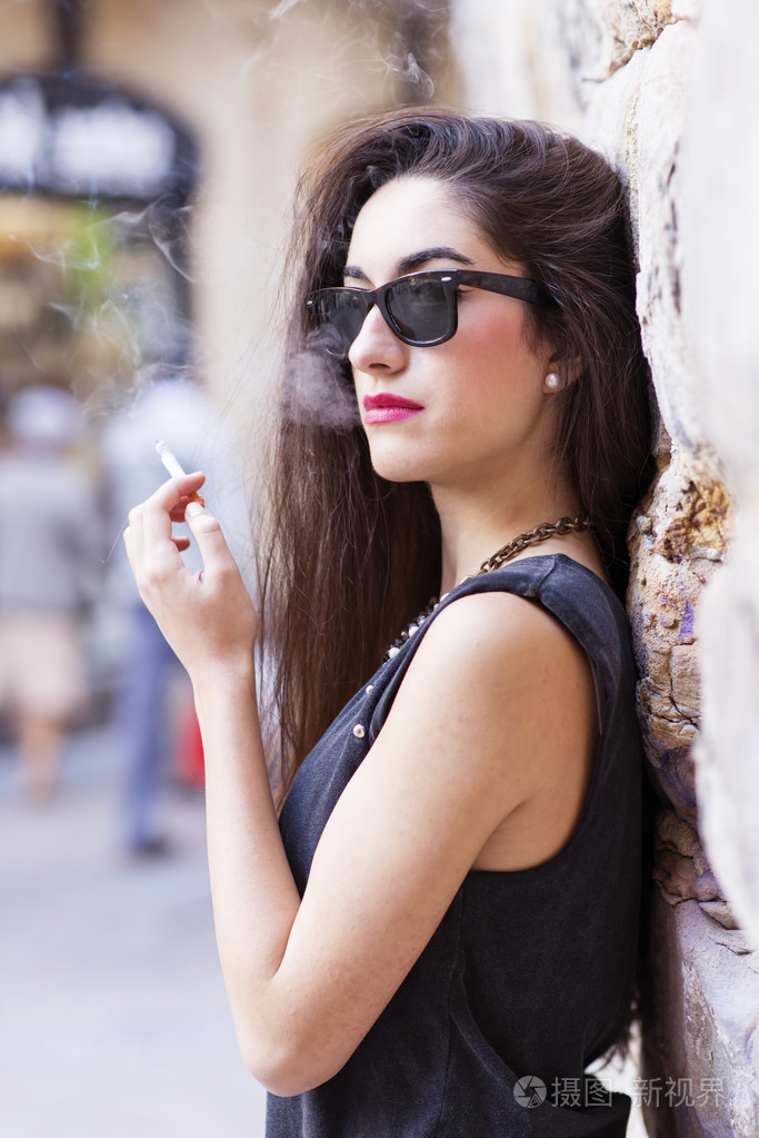 戴墨镜吸烟,复古风格的迷人黑发女子照片-正版商用图片1haqb5-摄图新