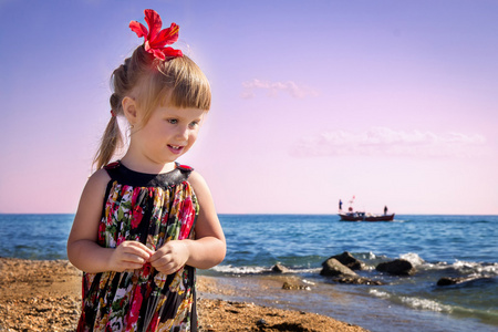 小女孩在沙滩上看着这艘船