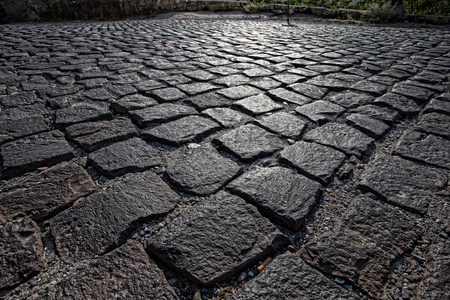 光的人行道上,路面纹理粗劣地制作石头大街块石面路背景
