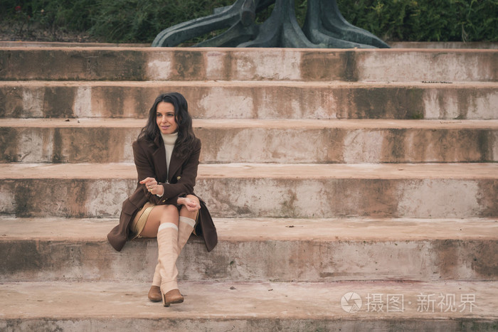 美丽的年轻女子坐在混凝土台阶上