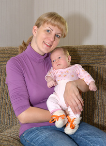 年轻女人正坐在沙发上抱着小孩的手上