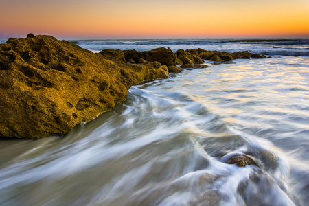 岩石和日出时在棕榈海岸大西洋海洋里的波浪