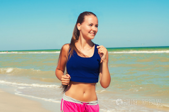 年轻漂亮的女孩运动员在沙滩上