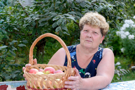 老太太提着篮子在花园里的苹果