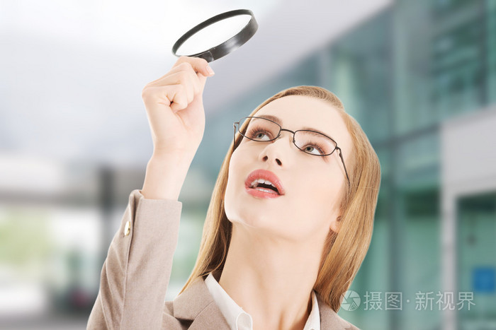 美丽的白种人商界女强人拿放大镜