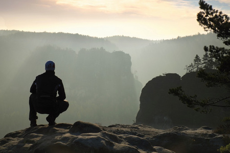 运动员是站在岩石帝国公园的石头上，看着雾气很重，有雾的早晨谷到太阳美丽一刻自然的奇迹