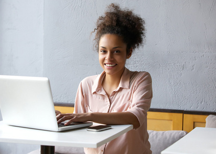 微笑笔记本电脑上工作的年轻黑人妇女