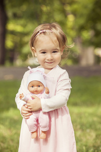 可爱的小女孩抱着一个娃娃婴儿户外
