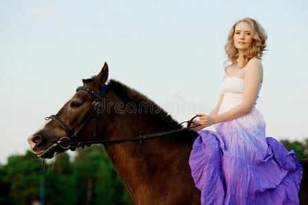 日落时在海滩上骑马的美女。在海边阳光下牵着一匹马的小女孩