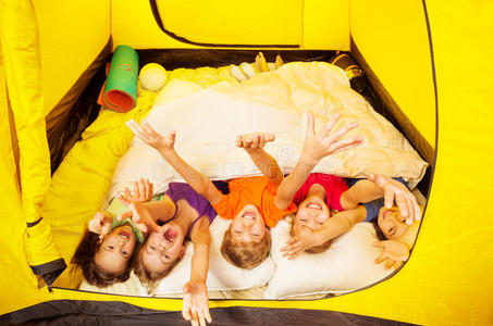五个孩子躺在帐篷里盖着毯子