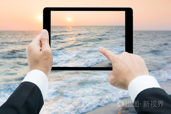 商人手拿平板电脑拍海滩和大海
