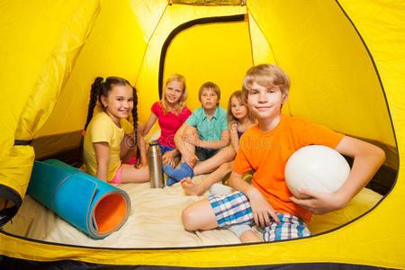 带着球的男孩和朋友在露营帐篷里