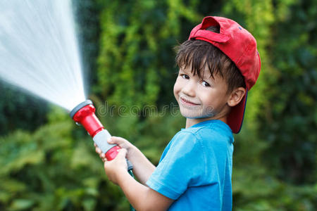 戴帽子的男孩把水倒在室外