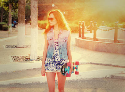 穿着休闲服的年轻女子手里拿着滑板站着
