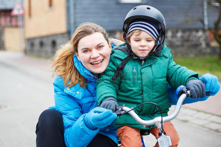 年轻的母亲在户外教她两岁的小儿子骑自行车。