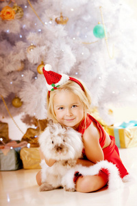 圣诞树旁美丽的圣诞小女孩。快乐的女孩