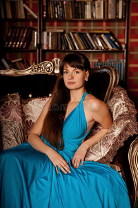 一个漂亮的女人穿着蓝色的长裙在富丽堂皇的室内。年轻的