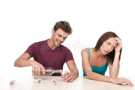 男人在倒酒，女人坐在桌旁不安。