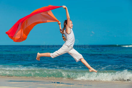 夏天在蓝色海岸的海滩上跳跃的少女