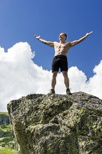 一个年轻人举着胳膊站在悬崖顶上