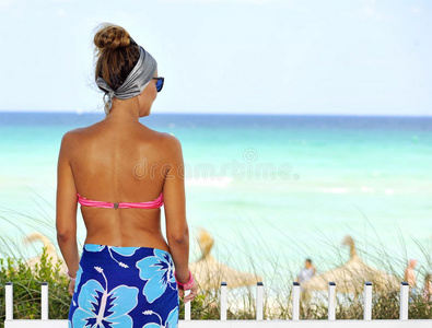 快乐的年轻漂亮的女人穿着粉色比基尼在天堂海滩摆姿势