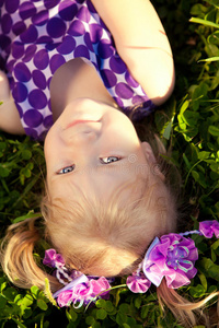 美丽的小女孩躺在公园的草地上。微笑的ch