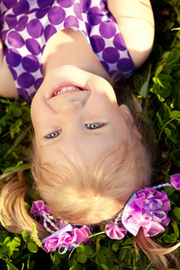 可爱的小女孩躺在公园的草地上。笑容可掬