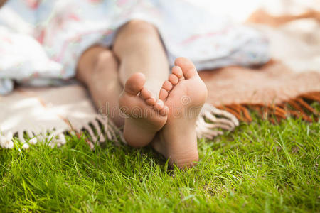 阳光明媚的日子里，女孩们的脚躺在草地上